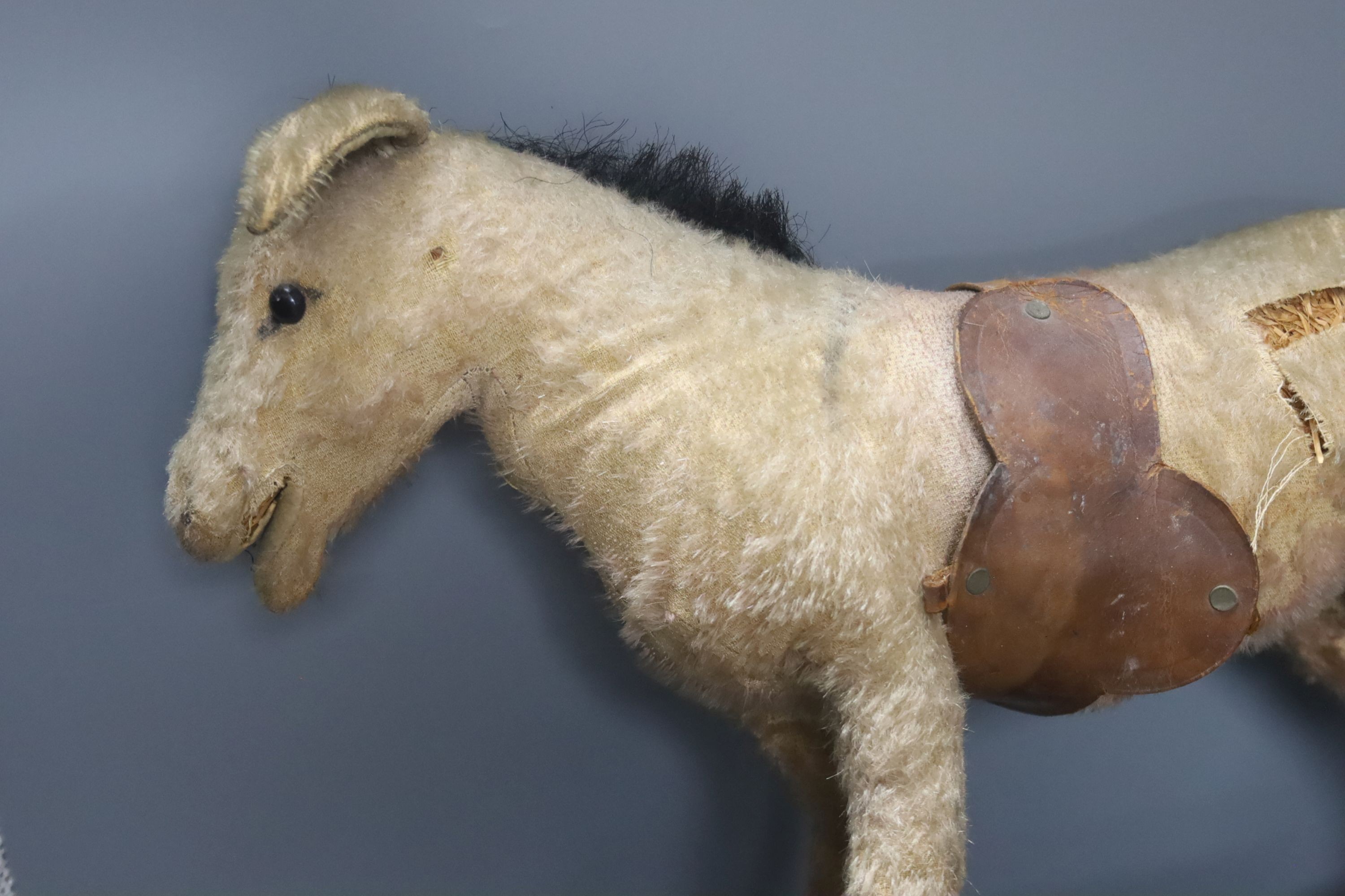 An early 20th century Steiff pull-along horse on wheels, boot button eyes and wood wool filling, button in left ear, 40cm long and a late 19th century painted plywood Noah's Ark with animals